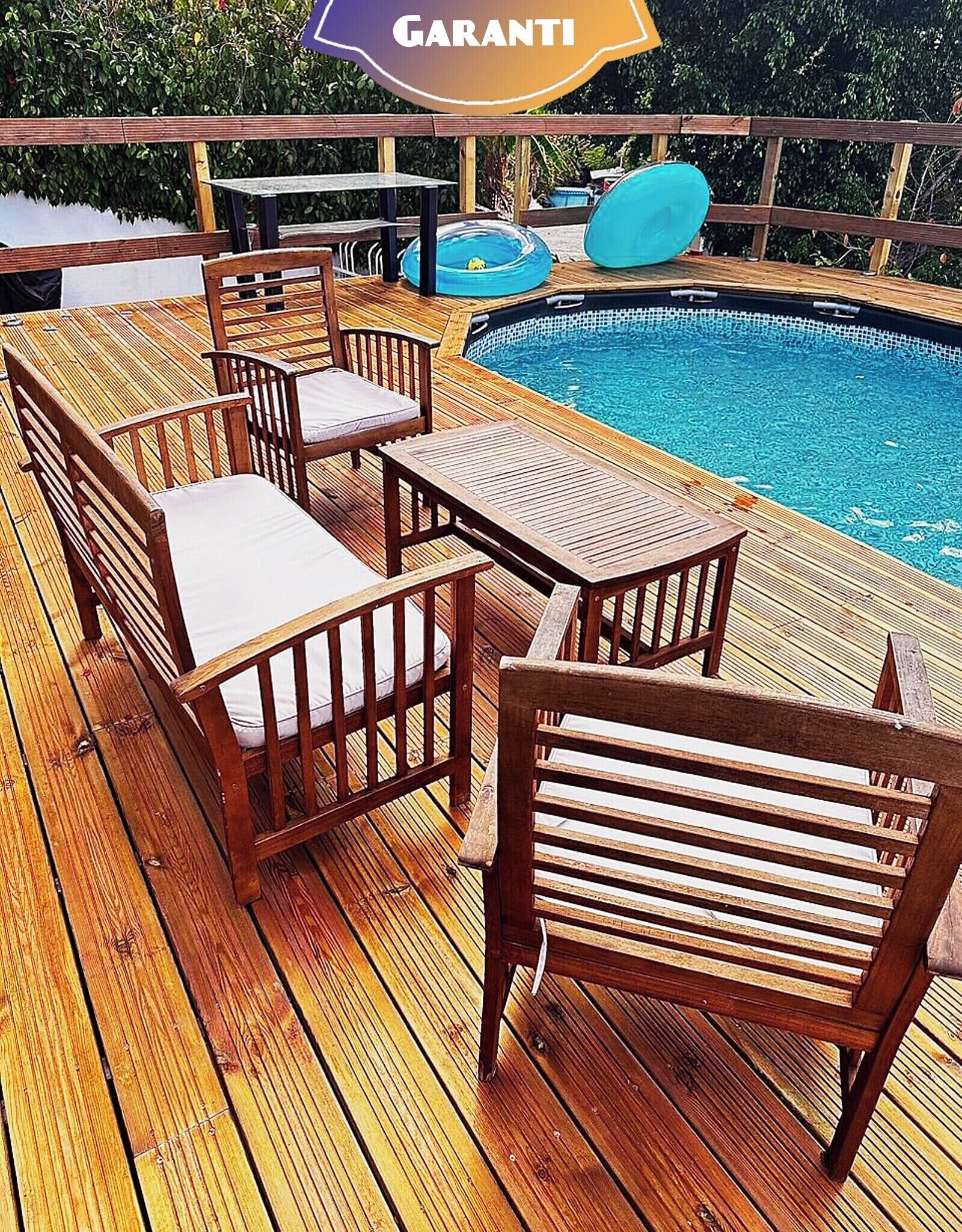A wooden deck with outdoor furniture, a pool, and a sign reading "GARANTI".