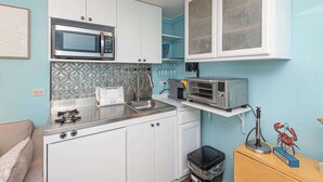 Eine kompakte Küchenzeile mit Mikrowelle, Toaster, Spüle und einem kleinen Mülleimer.