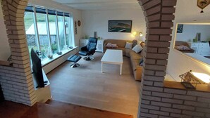 Un salon avec une grande fenêtre, un canapé, une table basse et un téléviseur.