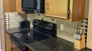 Una cocina con armarios de madera, un microondas negro, una estufa y un tostador.