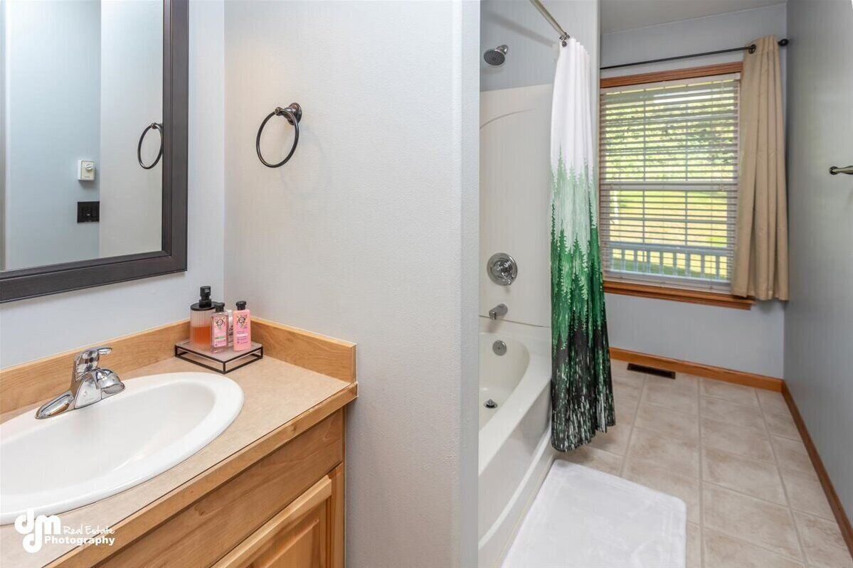 Un baño con lavamanos, espejo y zona de ducha.