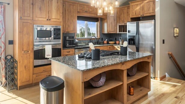 A modern kitchen with wooden cabinets, granite countertops, stainless steel appliances, and a central island. - Fleur de Lis 4bed 3bath & Mountain Views (Wasilla)