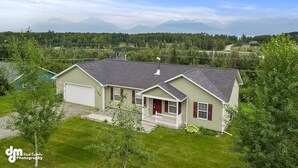 A single-story house with a garage, a front porch, and a view of mountains in the background. - Fleur de Lis 4bed 3bath & Mountain Views (Wasilla)