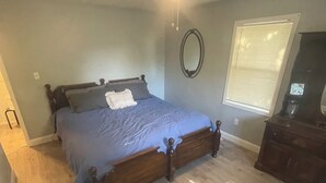 A bedroom with a wooden bed, a ceiling fan, a window with blinds, and a dresser. - Blue Pool House  (Lone Oak)