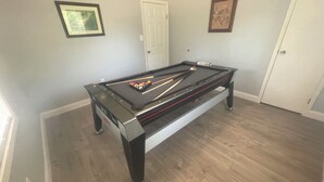 A pool table in a room with light gray walls, a white door, and a framed picture on the wall. - Blue Pool House  (Lone Oak)