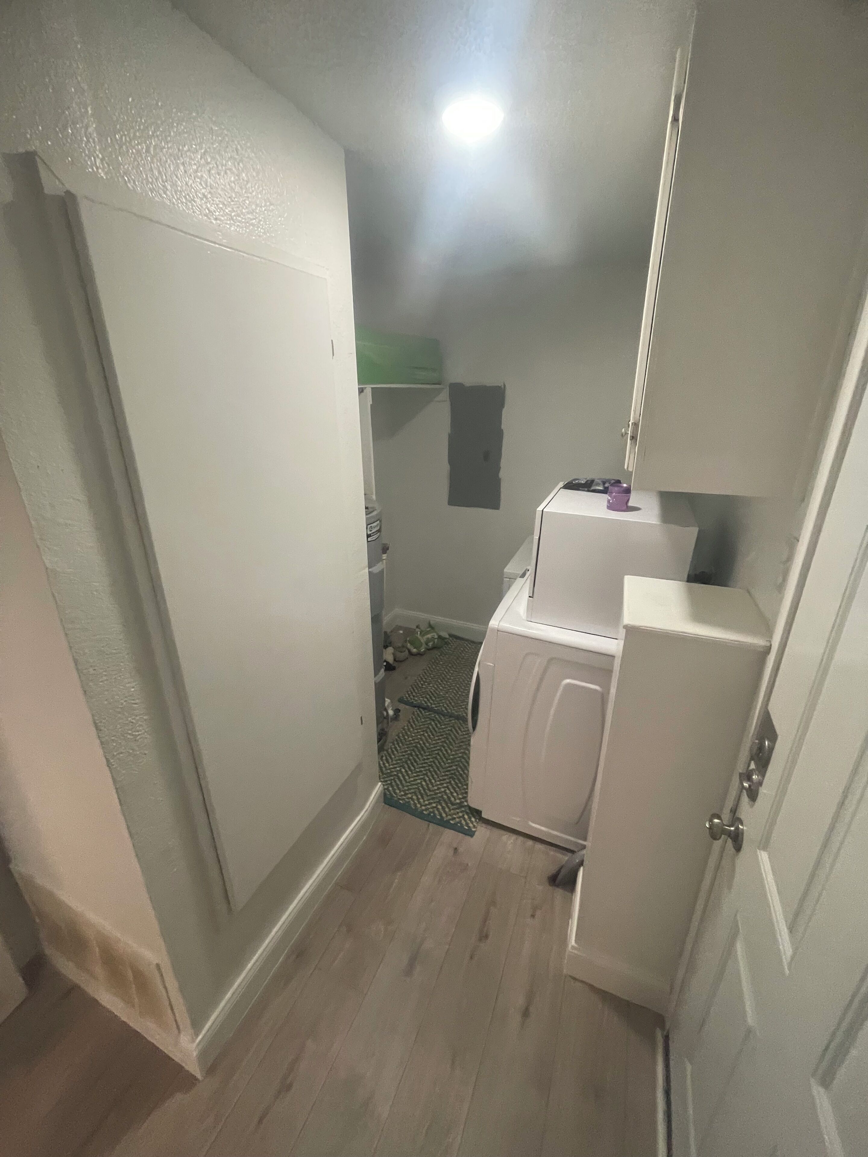 A laundry room with a washing machine, a dryer, and a small shelf with a purple object.