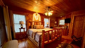 Um quarto aconchegante no estilo cabana, com cama de madeira, mesa de cabeceira, luminária e ventilador de teto.