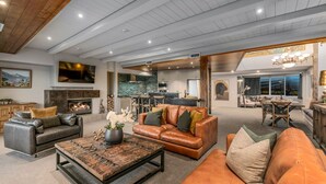 A spacious living area with leather sofas, a fireplace, and a kitchen in the background. - The Ballarat Apartment (Queenstown)
