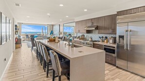 Una cocina moderna con una isla grande, electrodomésticos de acero inoxidable y vistas al exterior.
