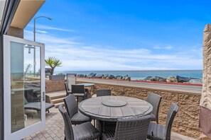 Une terrasse dotée de meubles en osier et d’une porte vitrée donnant sur la plage.