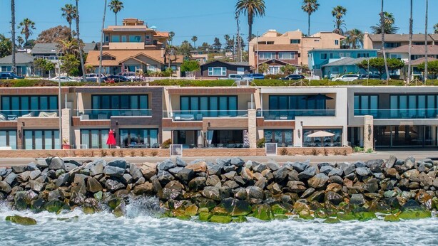Un hotel costero de arquitectura moderna, con costa rocosa y palmeras.