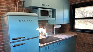 Une cuisine équipée d’un réfrigérateur Galanz, d’un four à micro-ondes et d’une fenêtre donnant sur les arbres.