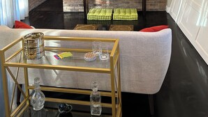 Un salon moderne avec un téléviseur à écran plat fixé sur un mur en briques, une table basse en verre agrémentée d’objets décoratifs, un canapé gris et une cheminée.