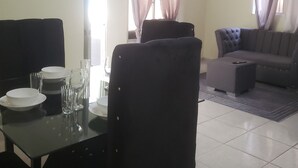 En stue med spisebord, stole, sofa og ventilator.