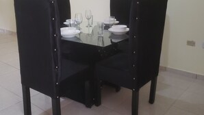 Et spisebord med fire stole, dækket med tallerkener, glas og bestik.