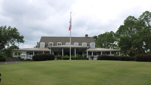 A large, two-story building with a covered porch and a flagpole.