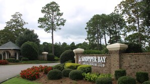 A brick wall with the sign "Sandpiper Bay Golf & Country Club" surrounded by well-maintained hedges and trees.