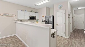 A kitchen with white cabinets, a refrigerator, and a sink.