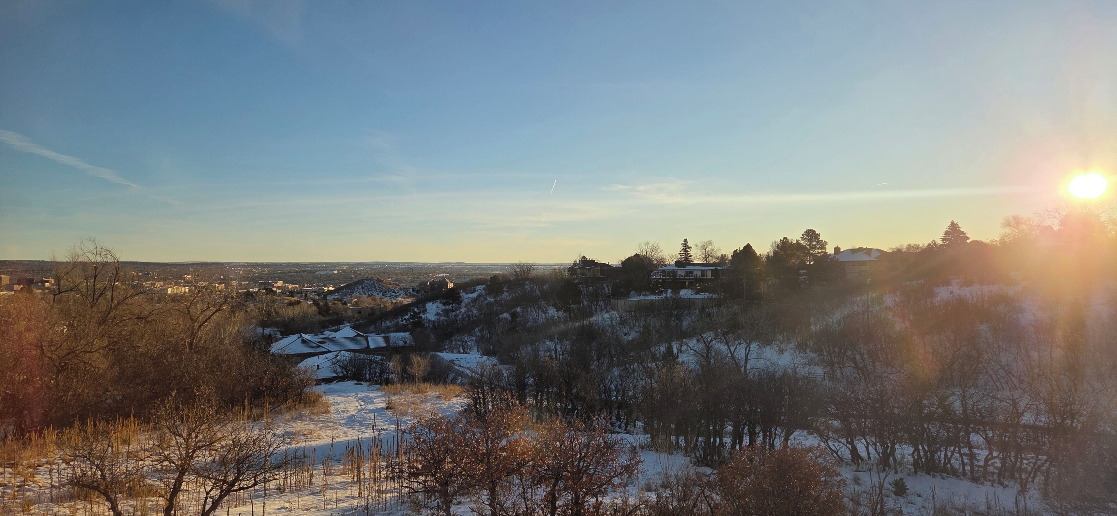 Een besneeerd landschap met een heldere lucht en de zon die onder- of opkomt.