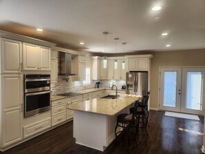 A modern kitchen with white cabinetry, stainless steel appliances, and a granite countertop.