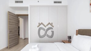Quarto de hotel com uma cama, um guarda-roupa, uma mesa de cabeceira e uma porta.