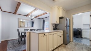 A kitchen with a central island, wooden beams on the ceiling, a built-in oven, and a washing machine in the adjacent room. - Cozy two bedroom home in Amarillo. Pet Friendly! (Amarillo)