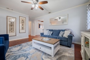 A living room with a blue sofa, a white coffee table, and a ceiling fan.