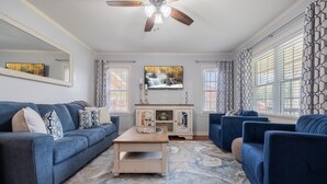 A living room with a blue sofa, a coffee table, and a TV on the wall. - Cozy two bedroom home in Amarillo. Pet Friendly! (Amarillo)