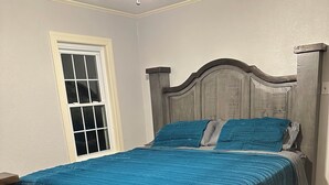 A bedroom with a wooden bed frame, a blue bedspread, and a patterned rug. - Cozy two bedroom home in Amarillo. Pet Friendly! (Amarillo)