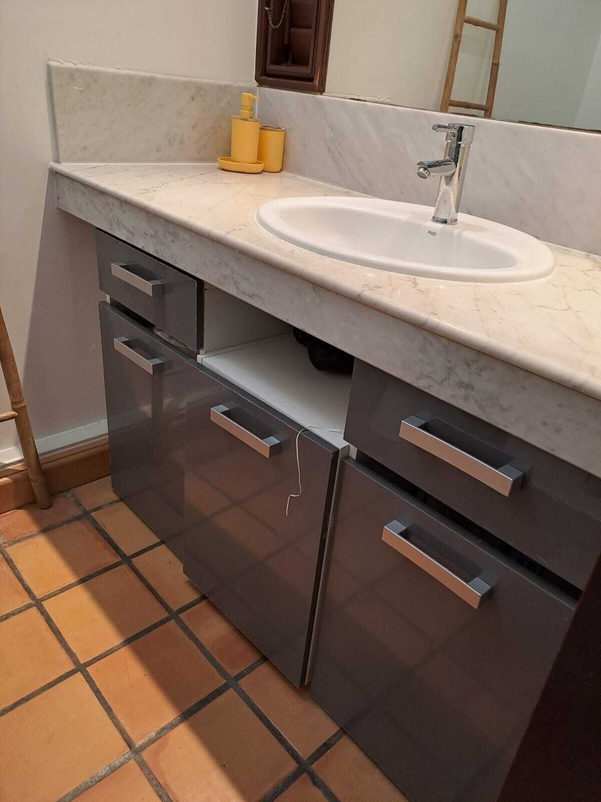 A bathroom with a white sink, dark cabinets, and a tiled floor.