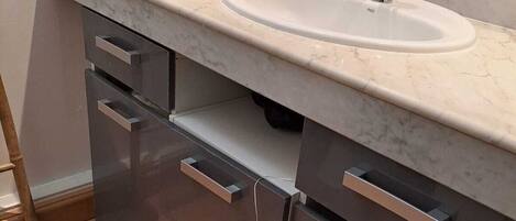 A bathroom with a white sink, dark cabinets, and a tiled floor.