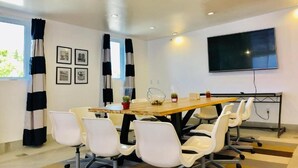A conference room with a long table, white chairs, a TV screen, and framed pictures on the wall. - Culver City Hostel (Culver City)