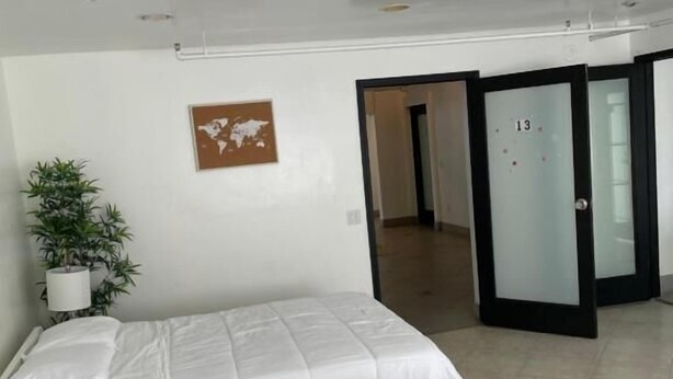 A modern hotel room with a bed, a potted plant, and a world map on the wall. - Culver City Hostel (Culver City)