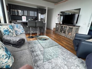 Een moderne woonkamer met een bank, een glazen salontafel en een televisie.