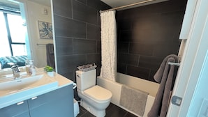 A modern bathroom with a toilet, sink, and shower area. - 18th floor 2 bed 2 bath overlooking downtown  (Winnipeg)