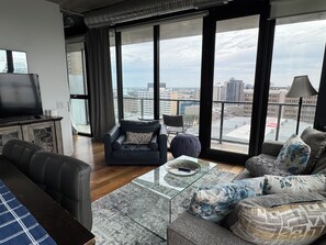 A modern living room with a sofa, armchair, and a glass coffee table. - 18th floor 2 bed 2 bath overlooking downtown  (Winnipeg)