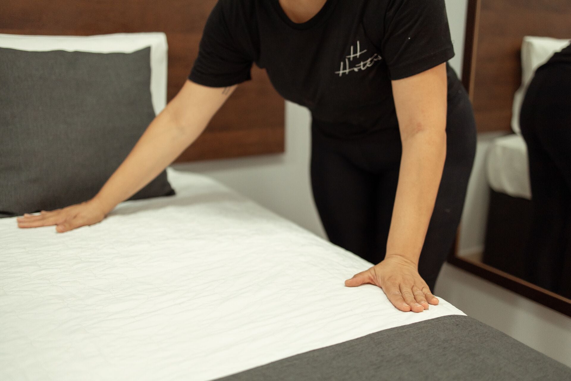 Una persona arreglando una cama en una habitación de hotel.