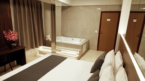 Una camera d'albergo con un letto, una scrivania, uno specchio, una vasca da bagno e una porta.