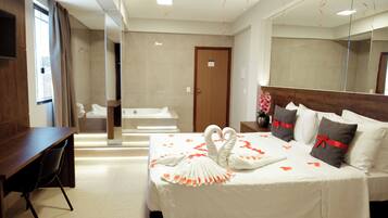 Une chambre d’hôtel équipée d’un lit, d’un bureau, d’une chaise, d’une baignoire et d’un grand miroir.