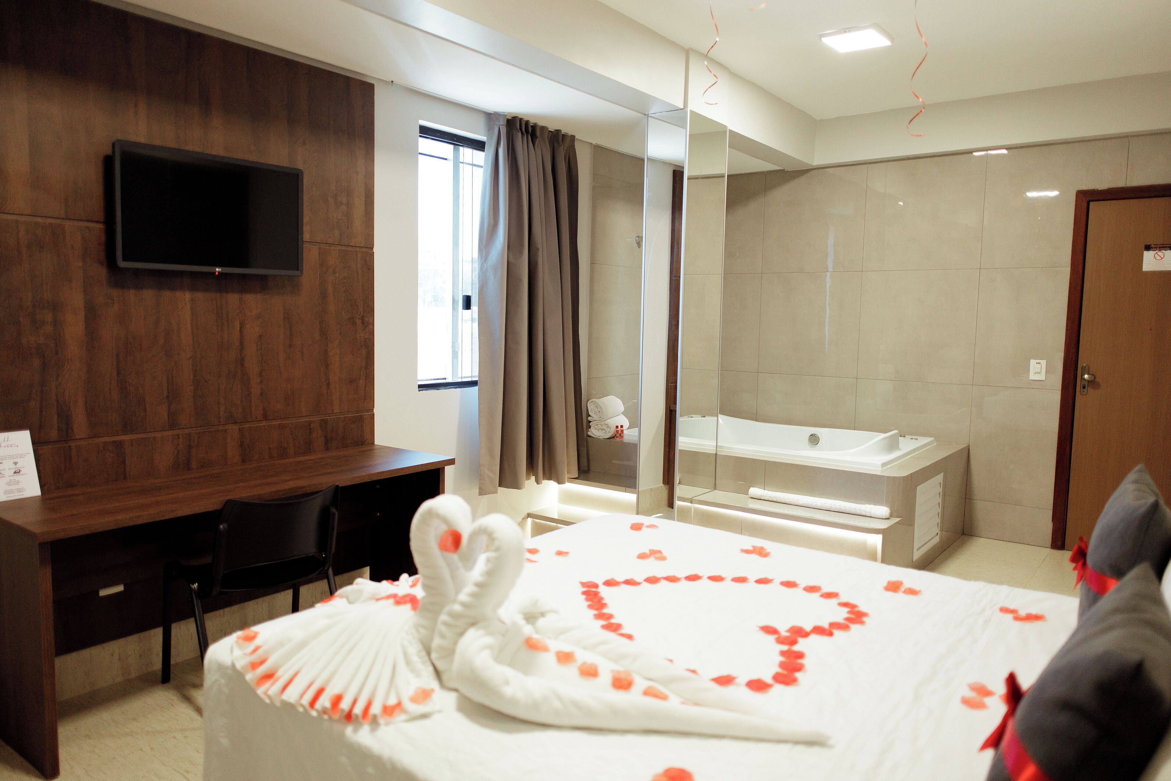 Una habitación de hotel con cama, escritorio, televisor, baño y ducha.