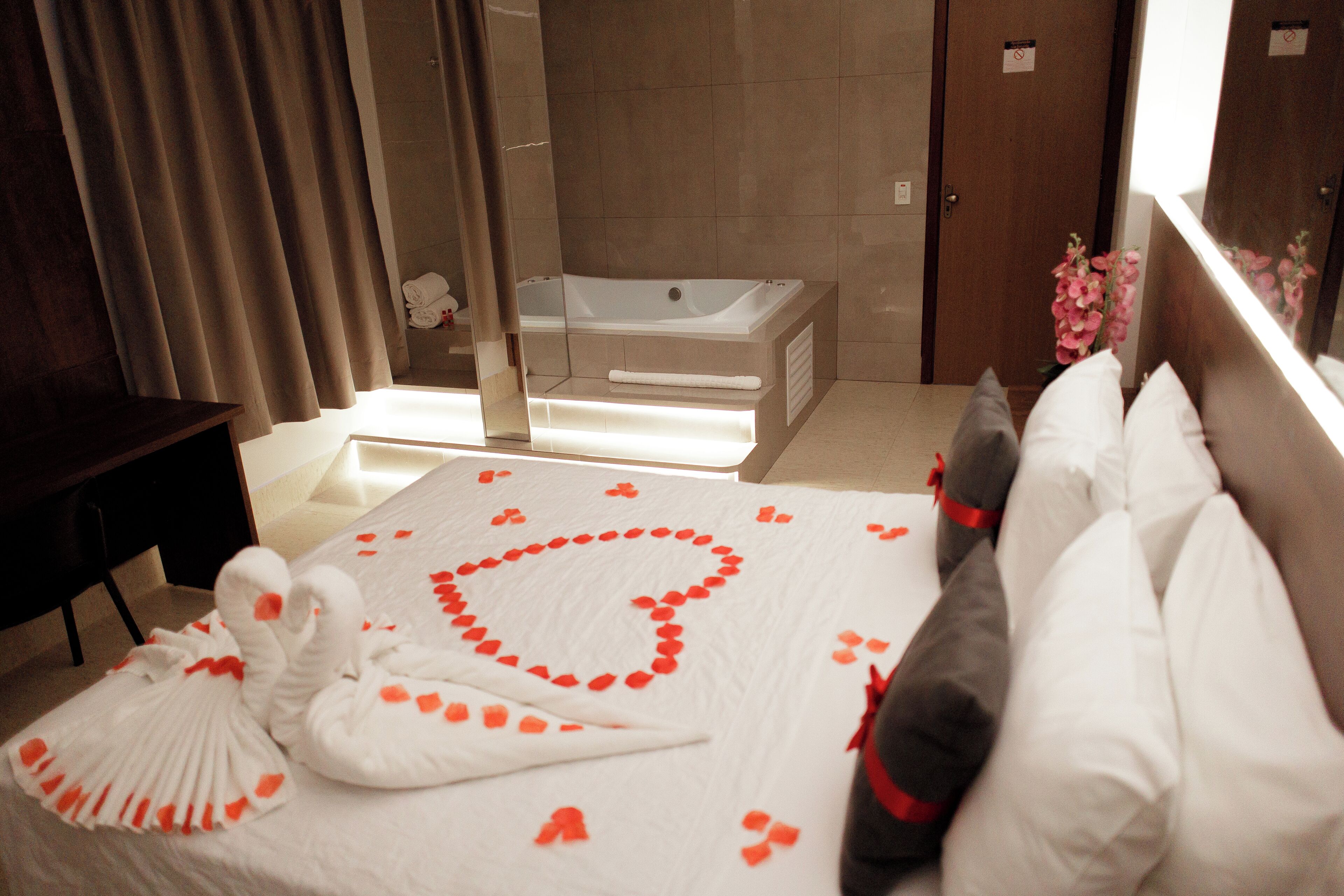 A hotel room with a large bed, a bathtub, and a mirror.