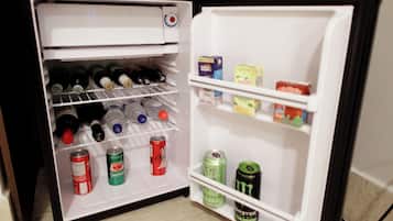 An open refrigerator with shelves containing beverages and snacks.