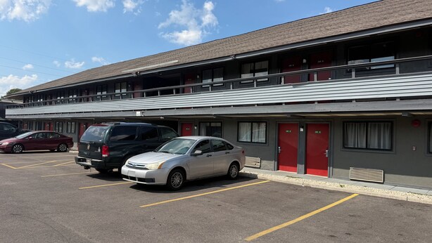 Un motel con parcheggio, diverse camere ed un edificio a due piani.