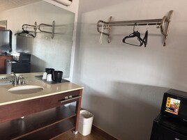 Un baño con lavabo, espejo, toallero y microondas.