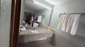 Un bagno con lavabo su piano in granito, uno specchio e un portasciugamani.