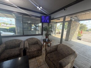 Una habitación con dos sillones de estampado floral, una mesita con una botella de agua y un televisor montado en la pared.