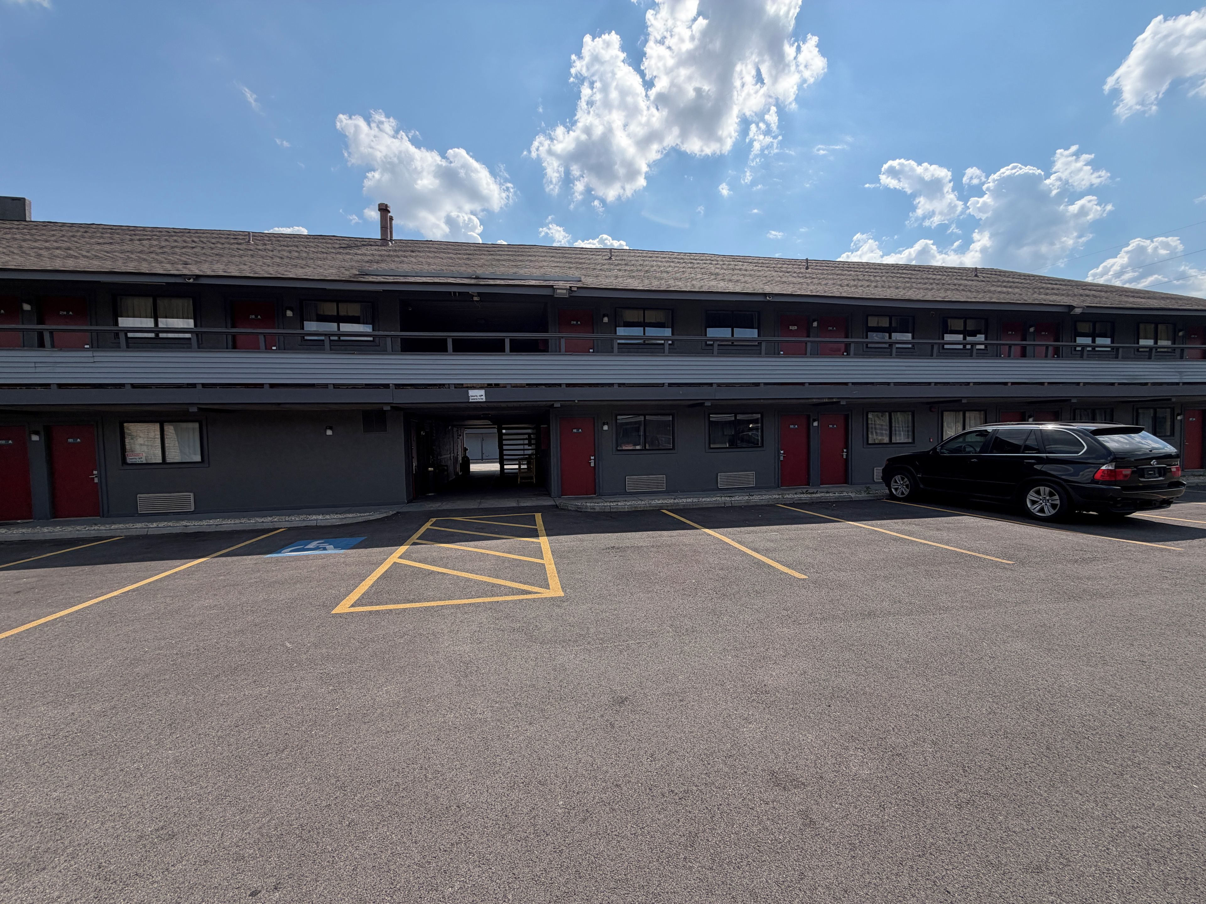 A multi-story parking garage with a black car parked in the lot.