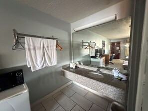 A bathroom with a large mirror, a sink, a towel rack, and a washing machine.