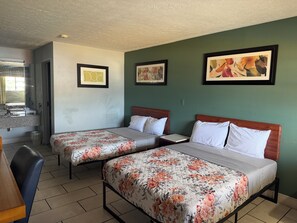 A hotel room with two beds, a bathroom, and a small seating area.