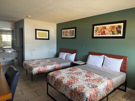 Habitación de hotel con dos camas, baño y un pequeño rincón de descanso.
